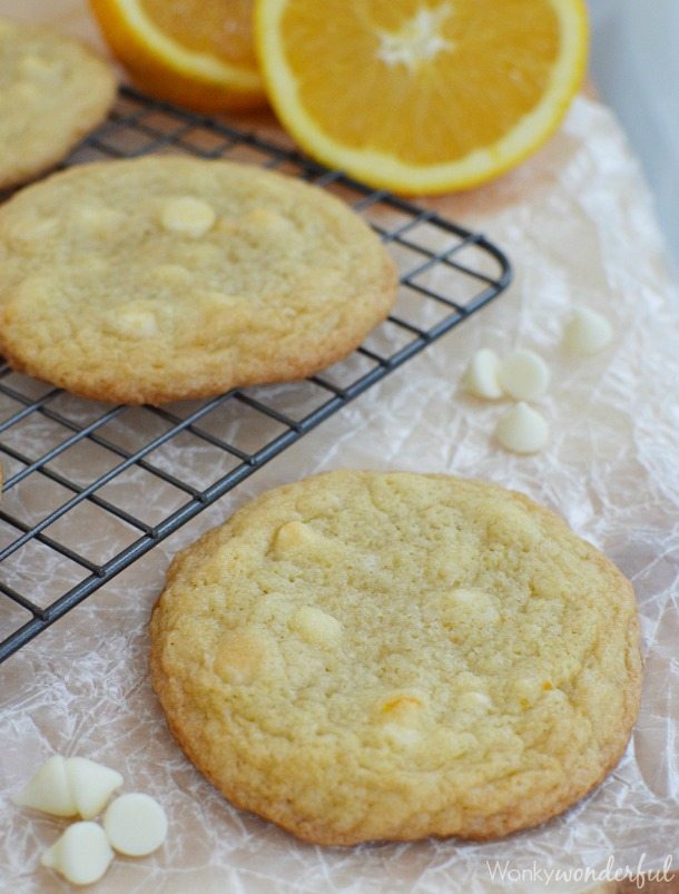 white chocolate chips and golden cookies next to cooling rack and orange sliced in half