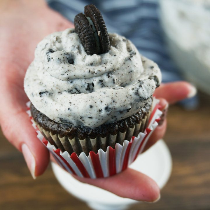 hand holding cupcake topped with cookies and cream frosting