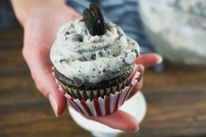 hand holding cupcake topped with cookies and cream frosting