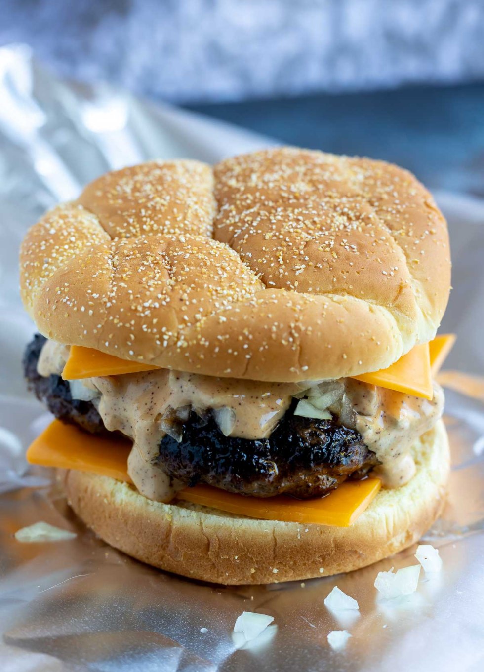 cooked burger on bun with cheese slices and sauce before being baked