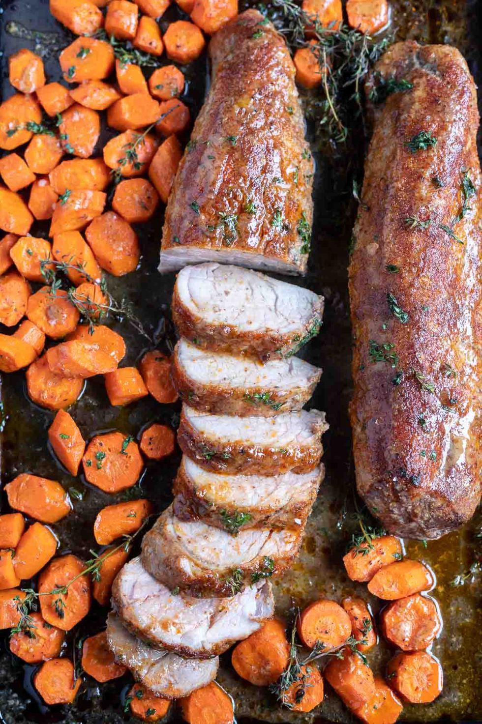 partially sliced pork tenderloin and carrots on sheet pan