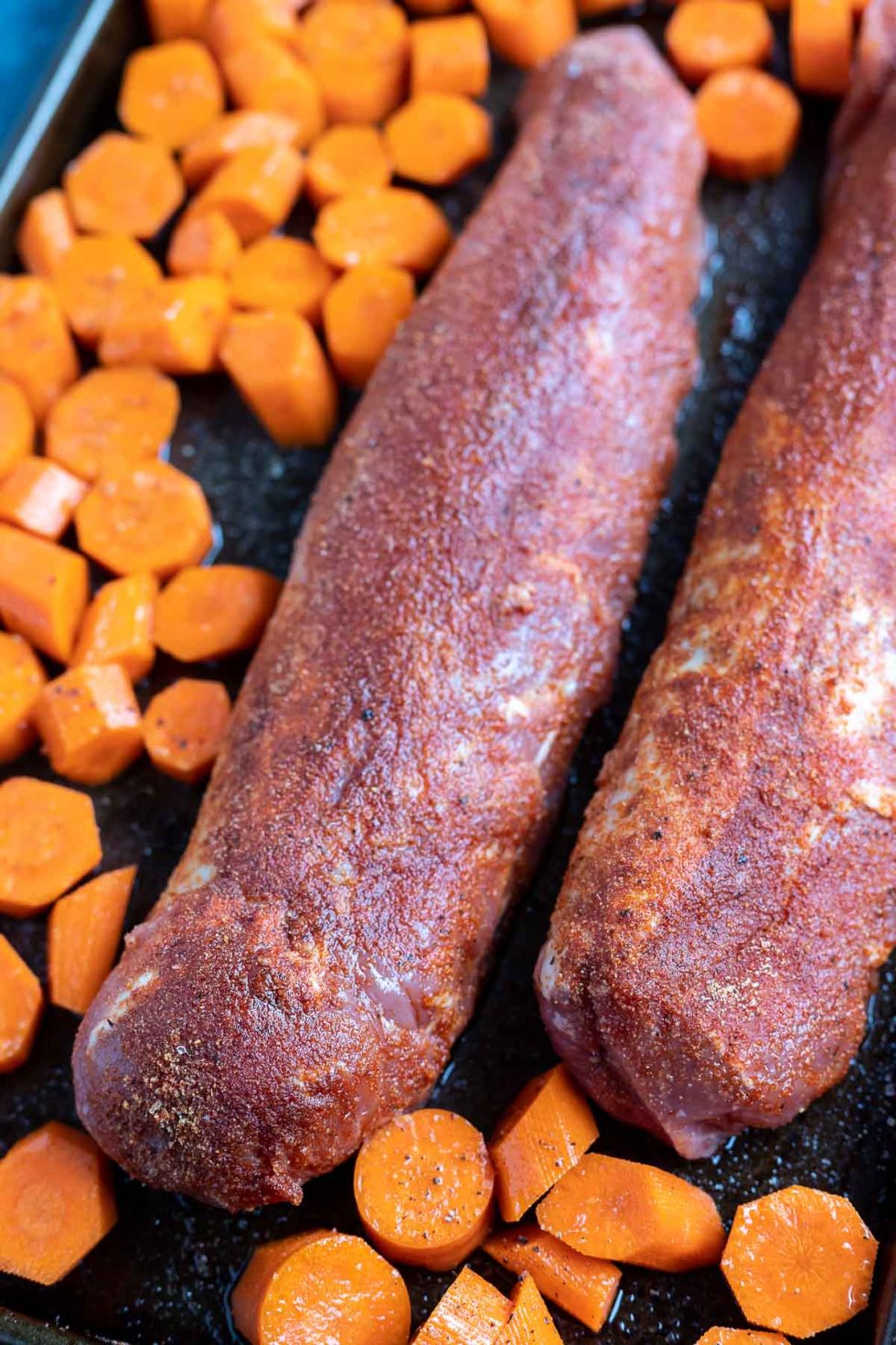 raw pork tenderloin and carrots on sheet pan