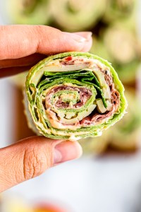 hand holding rolled pastrami pinwheel