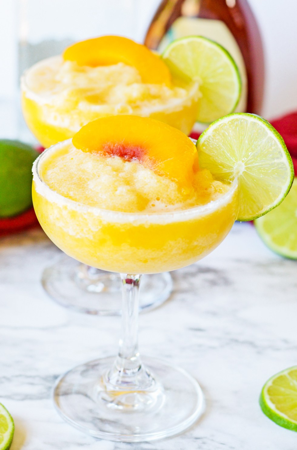 peach cocktails in tall glasses topped with lime and peach