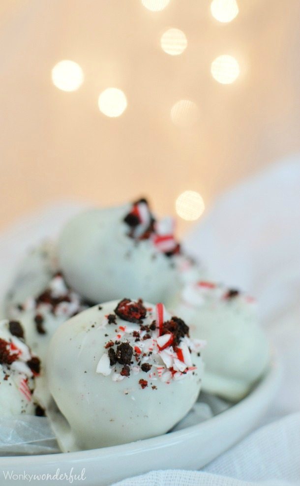 white candy coated balls topped with crushed Oreos and candy cane in white dish