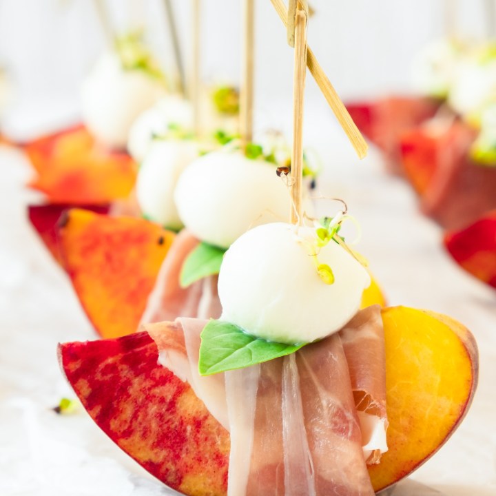 peach wedge wrapped with prosciutto topped with mozzarella ball and basil