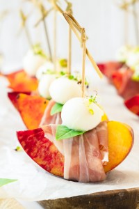 peach wedge wrapped with prosciutto topped with mozzarella ball and basil