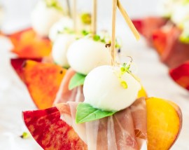 peach wedge wrapped with prosciutto topped with mozzarella ball and basil