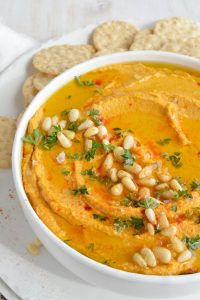 pumpkin hummus in white bowl with crackers on the side