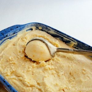 peach ice cream in blue dish with silver ice cream scoop