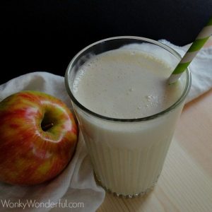 overhead view of creamy smoothie in clear glass next to apple