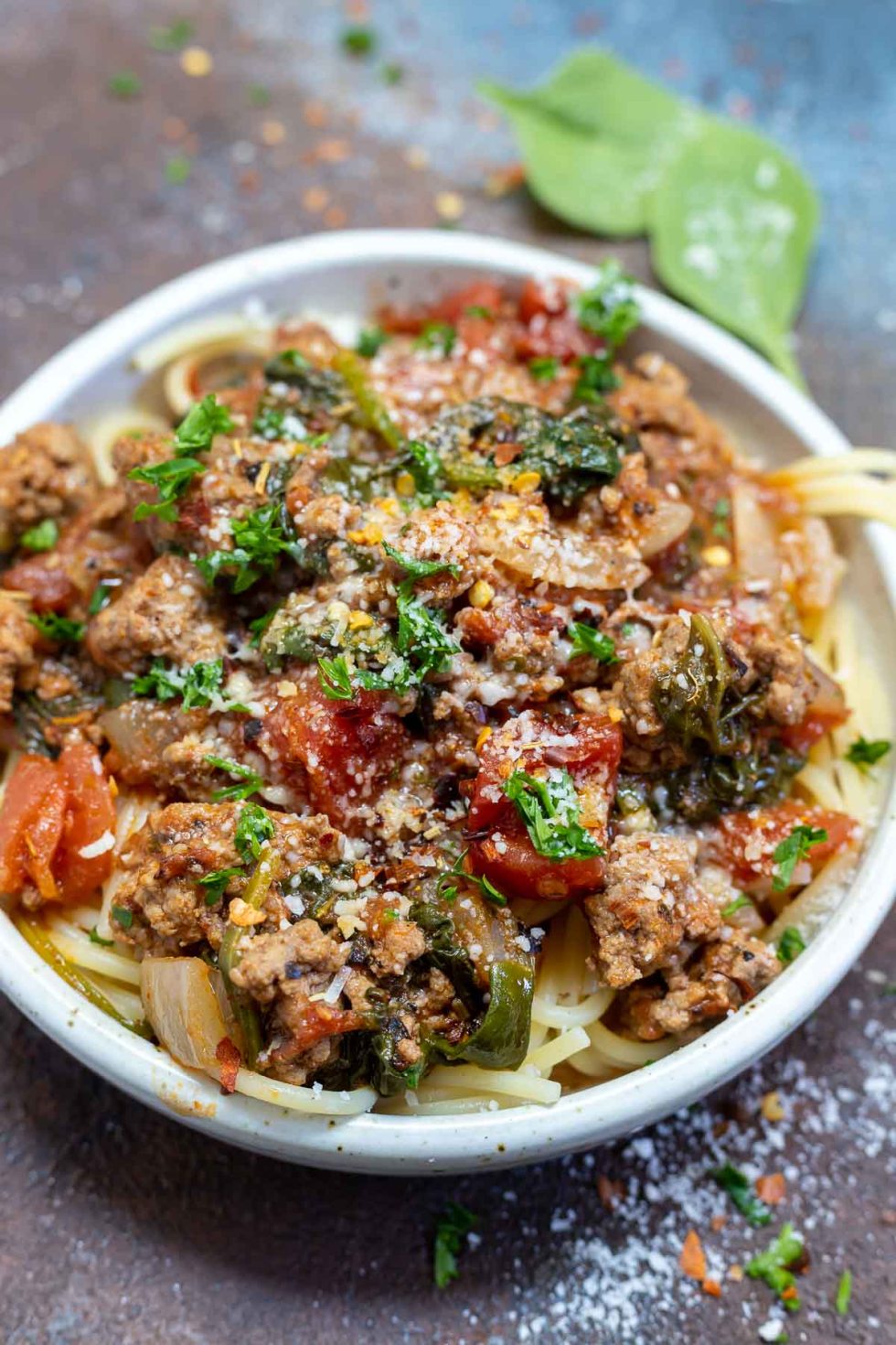 meat sauce served over cooked spaghetti in white bowl