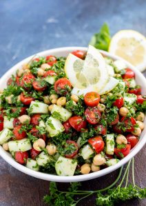 chickpea tabouli salad topped with lemon slices served in white bowl