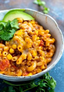 white bowl filled with cheesy taco casserole topped with cilantro and avocado