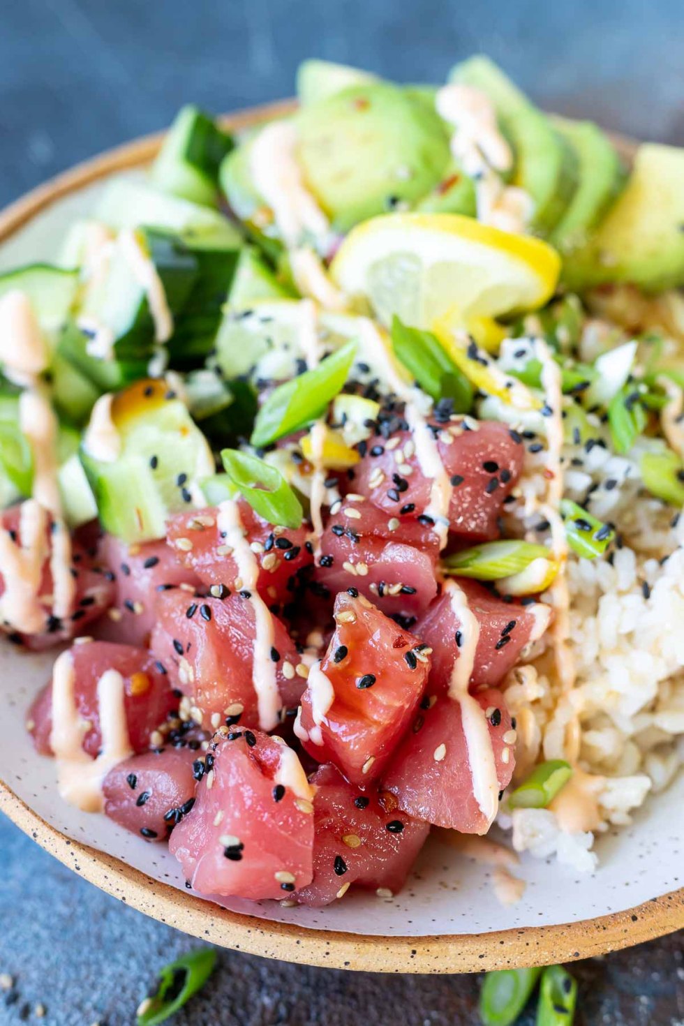 raw tuna, rice, cucumbers and avocado topped with sauce 