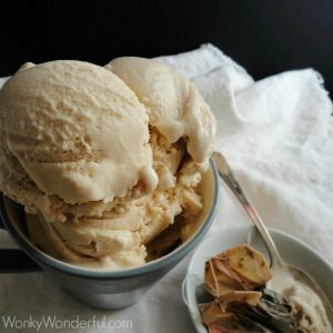 scoops of tan ice cream in blue mug next to tea bags and spoon