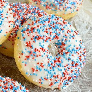 These Homemade Baked Donuts are a simple vanilla cake, thick glaze and nonpareils sprinkles. Red, White and Blue Doughnuts make the perfect 4th of July dessert recipe!