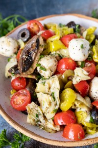 tomatoes, artichokes, mushrooms and mozzarella balls in white bowl