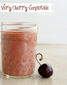 red cherry smoothie in clear glass mason jar with cherry on the side, photo text: very cherry smoothie